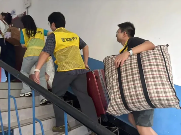 老师帮学员把行李搬上宿舍楼
